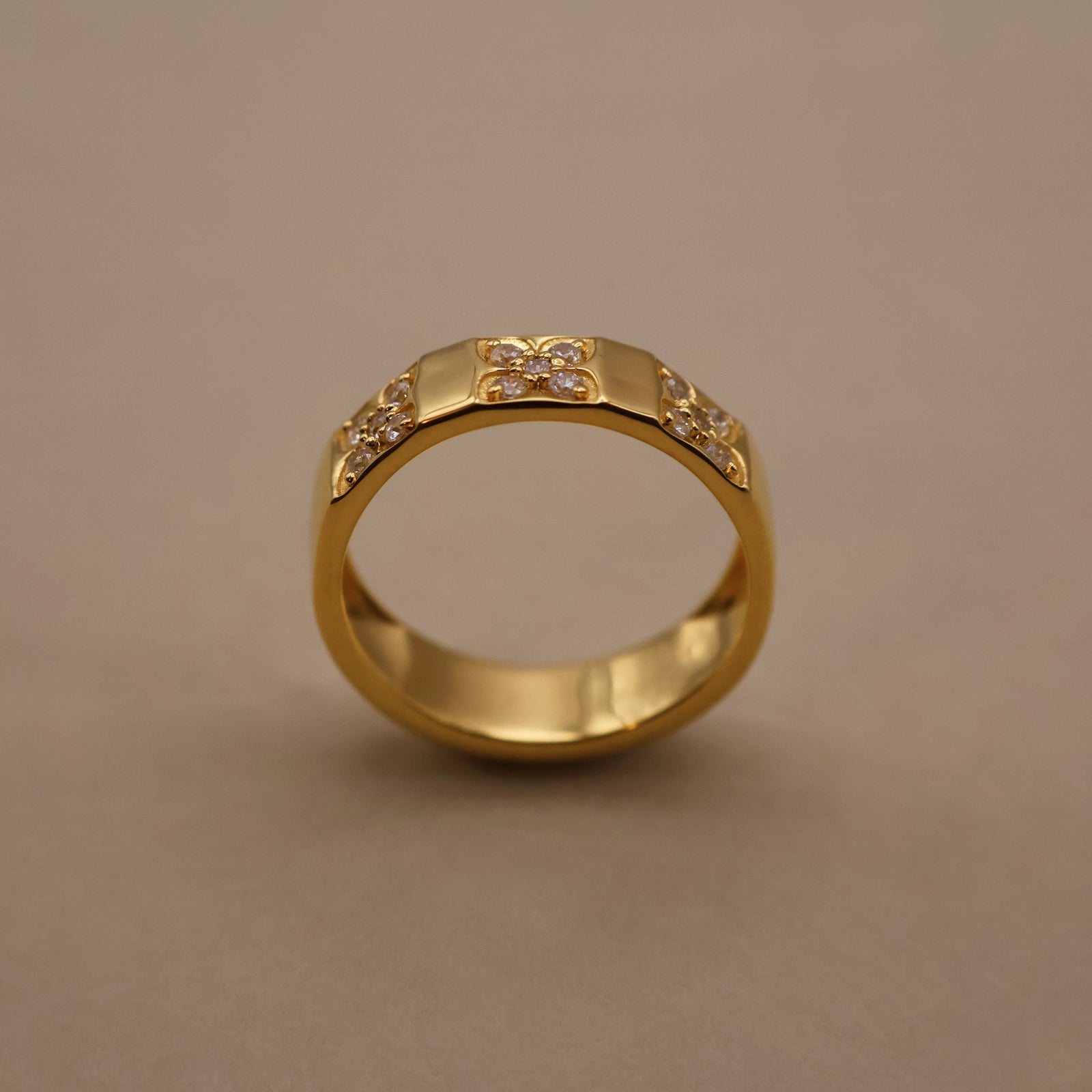 Gold ring with floral designs on a beige background